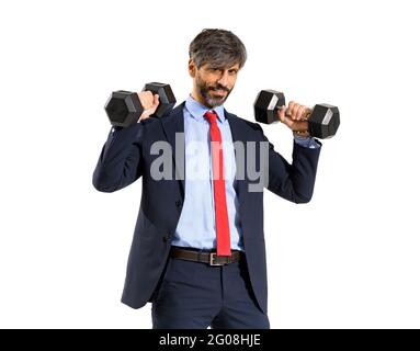 Stylish fit businessman in suit working out with gym weights raising up two dumbbells with a smile in a healthy active lifestyle concept isolated over Stock Photo