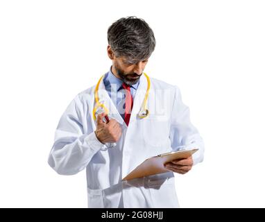 Doctor in white lab coat and stethoscope standing consulting patient records or notes on a handheld clipboard with an engrossed serious expression iso Stock Photo