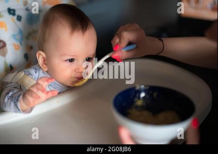 Woman's hand feeding her baby son with spoon Stock Photo