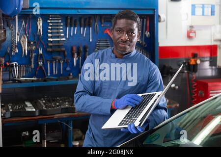 Mechanic using a laptop to work in service Stock Photo