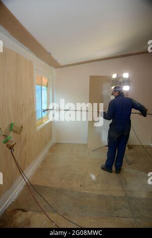 a tradesman using airless spray equipment to paint a primer coat on the walls of a commercial building Stock Photo