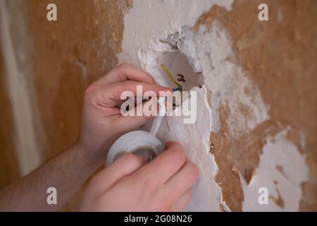 Closeup of an electrician putting two cables together and adding insulating tape on them Stock Photo