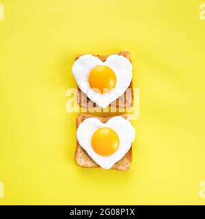 Heart shaped egg in tosted slice of rye bread. Love breakfast design. Healthy sandwich. Festive lunch or breakfast. Egg day. Stock Photo