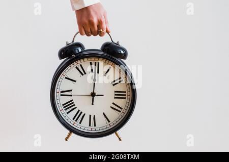Female hand holding a big vintage alarm clock Stock Photo