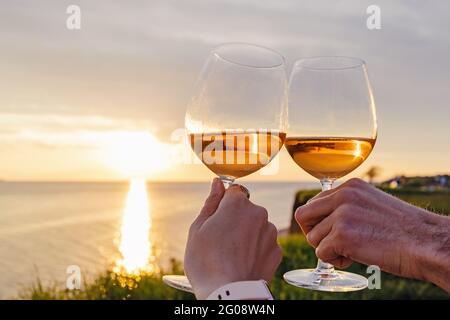 Couple clinking with two glasses of rose wine on sunset Stock Photo