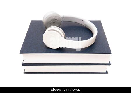 Two thick books with wireless headphones on top isolated on white. Distant learning concept. Stock Photo