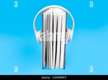 Thick book with wireless headphones isolated on blue background Stock Photo
