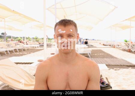 Portrait of a smiling man with sunscreen on his face on beach Stock Photo