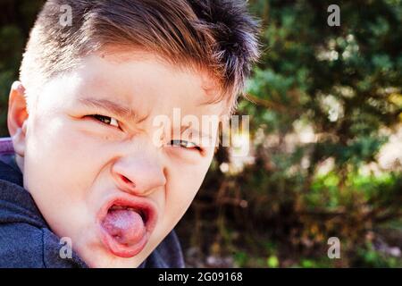 boy pulling a face in park Stock Photo