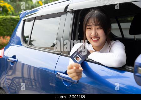 Attractive young Asian woman proudly showing driver license Stock Photo