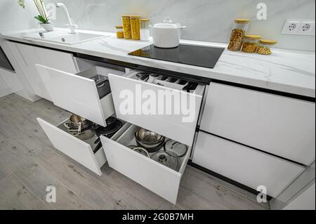 Luxurious white and black modern kitchen interior, drawers pulled out Stock Photo