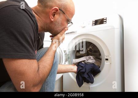 Male loading the washing machine with dirty clothes Stock Photo