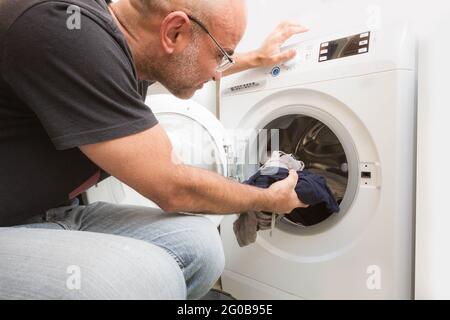Male loading the washing machine with dirty clothes Stock Photo