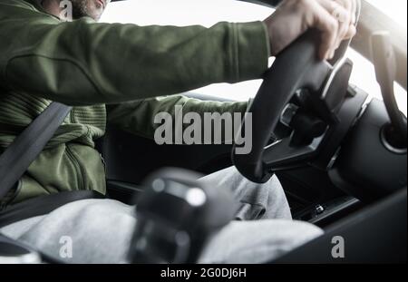 Caucasian Men Behind the Car Steering Wheel. Driving Performance Vehicle. Interior View. Stock Photo