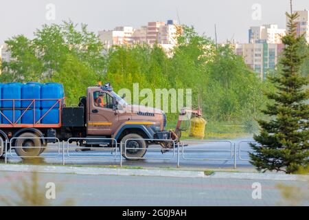 A special machine irrigates the road in the city, removing garbage and dampening the asphalt from the heat. Stock Photo