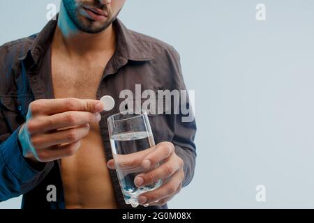 Man throw pill in glass with water, close up Stock Photo