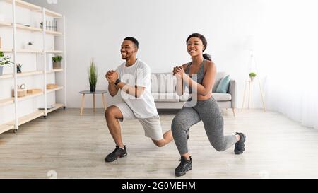 Home fitness. Full length of motivated black couple doing lunges in living room, banner design Stock Photo