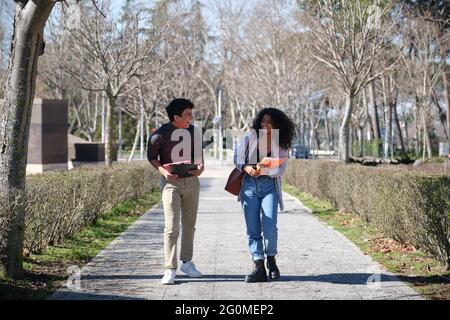 Two latin students walking and laughing at the college campus. University life. Stock Photo