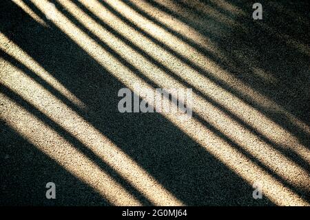 Bright sunlight and hard black shadows on the road. Shadow stripes on an asphalt road. Stock Photo