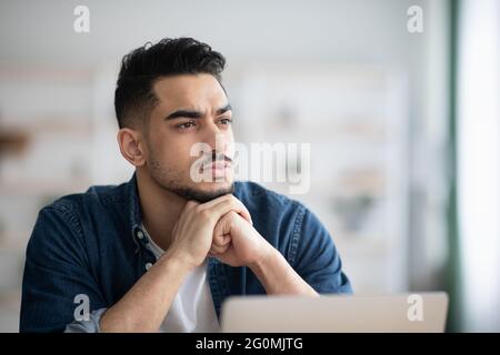 Thoughtful arab man employee working on laptop Stock Photo