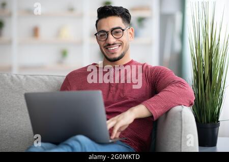 Positive arab man freelancer working from home, using notebook Stock Photo