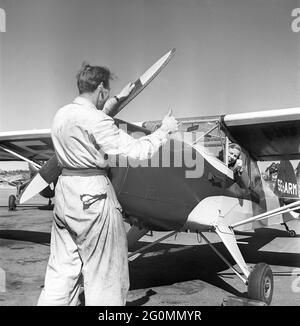 Woman pilot in the 1950s. Sweden's only flying waitress. Rut Berggren from Sundsvall has taken her flight certifikate in a Stockholm airplane club and is seen here in the cockpit giving thumbs up to a mechanic prior a flight. Sweden 1952. ref AY38-7 Stock Photo