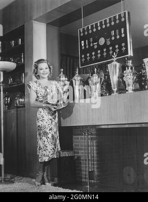Sonja Henie. Norwegian figure skating champion, born april 8 dead october 12 1969. Pictured in her Hollywood home with parts of her trophy collection. Medals and silver trophys fills the wall and on the shelves. 1940s. Stock Photo