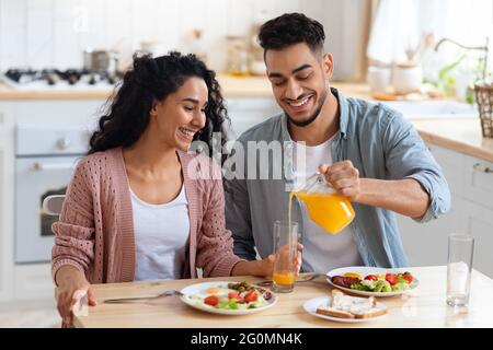 Morning Meal. Arab Spouses Eating Breakfast And Drinking Orange Juice In Kitchen Stock Photo