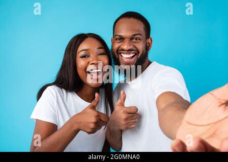 Happy afro couple taking selfie gesturing thumbs up and smiling Stock Photo