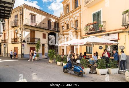 Monreale, Sicily, Italy - October 8, 2017: People enjoying the street bar in a narrow street in the historic center of Monreale. Stock Photo