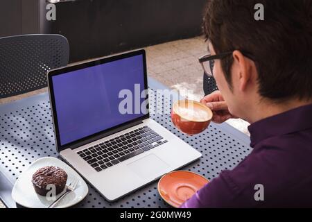 Asian businessman using laptop with blank screen drinking coffee in cafe Stock Photo