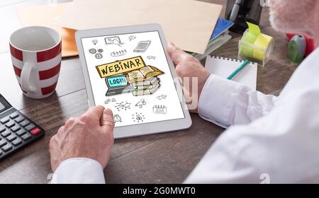Webinar concept shown on a tablet held by a man Stock Photo