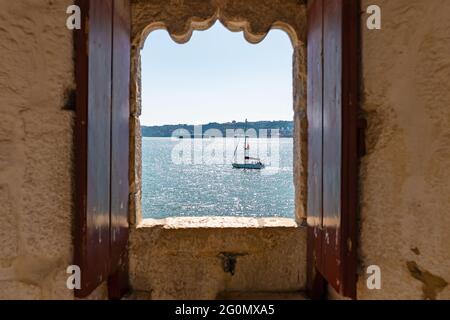 Small boat seen through an old window of an ancient fort Stock Photo