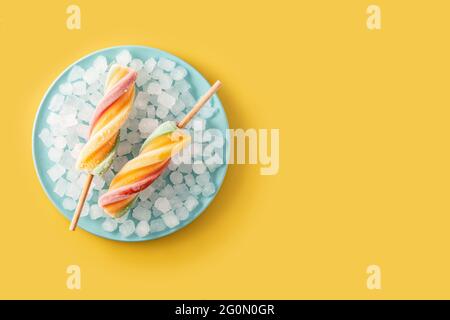 Spiral colorful popsicles on yellow background Stock Photo