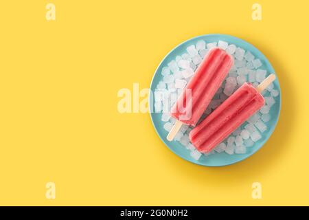 Strawberry popsicles with ice on yellow background Stock Photo