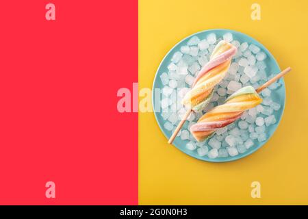 Spiral colorful popsicles on red and yellow background Stock Photo