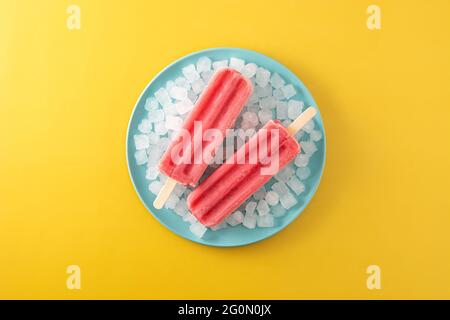 Strawberry popsicles with ice on yellow background Stock Photo