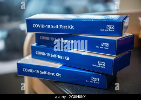 COVID-19 Self-Test Kits stacked in a pile on a table.  Side of the blue COVID test kit clearly showing Stock Photo
