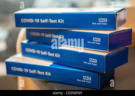 COVID-19 Self-Test Kits stacked in a pile on a table.  Side of the blue COVID test kit clearly showing Stock Photo