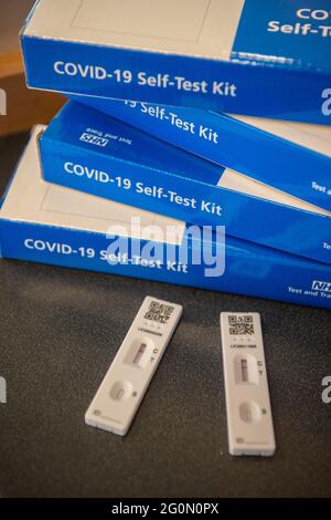 COVID-19 Self-Test Kits stacked in a pile on a table.  Side of the blue COVID test kit clearly showing Stock Photo