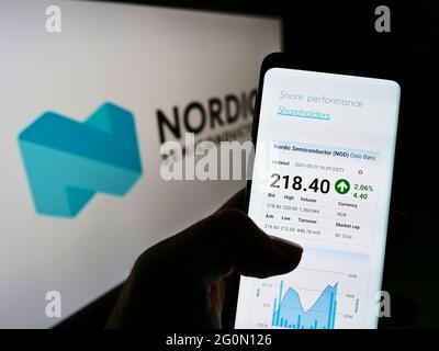 Person holding cellphone with webpage of Norwegian company Nordic Semiconductor ASA on screen in front of logo. Focus on center of phone display. Stock Photo