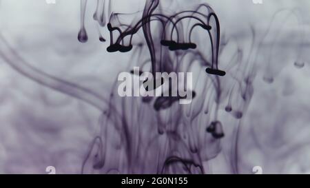 Photo of drops of purple paint falling in water Stock Photo