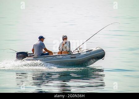 Fishermen with spinning go fishing on sea on rubber inflatable boat. Crimea, Sudak - 10 October 2020. Stock Photo