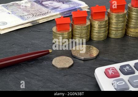 A still life with stacks of pound coins that have toy houses on top. A metaphor on property finance. Stock Photo