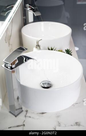 Pair of ceramic water basins in the interior of light modern bathroom with a mirror with light Stock Photo