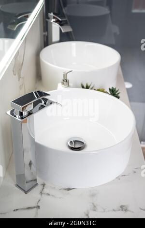 Pair of ceramic water basins in the interior of light modern bathroom with a mirror with light Stock Photo