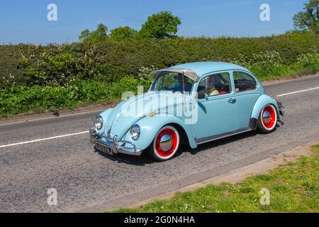 1971 70s blue Vw old type 1 Volkswagen Beetle, 1285cc with white wall tyres and red wheels, driving on country roads en-route to Capesthorne Hall, classic car show in Cheshire, UK Stock Photo