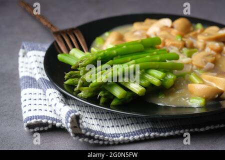 Asparagus green, and mushroom on plate on black background  Stock Photo
