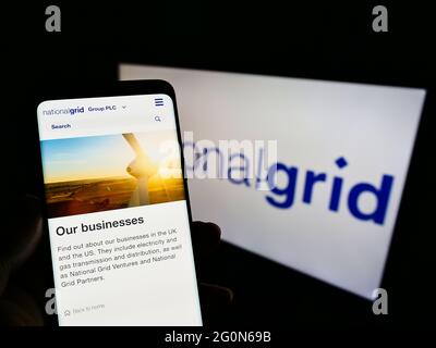 Person holding mobile phone with website of British utility company National Grid plc on screen in front of logo. Focus on center of phone display. Stock Photo
