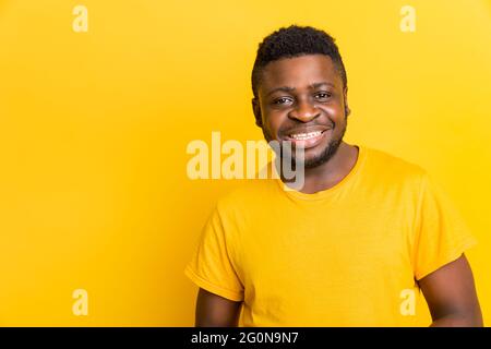 Head shot smiling african american millennial young man wearing trendy yellow t-shirt, looking at camera isolated on blank yellow studio background Stock Photo